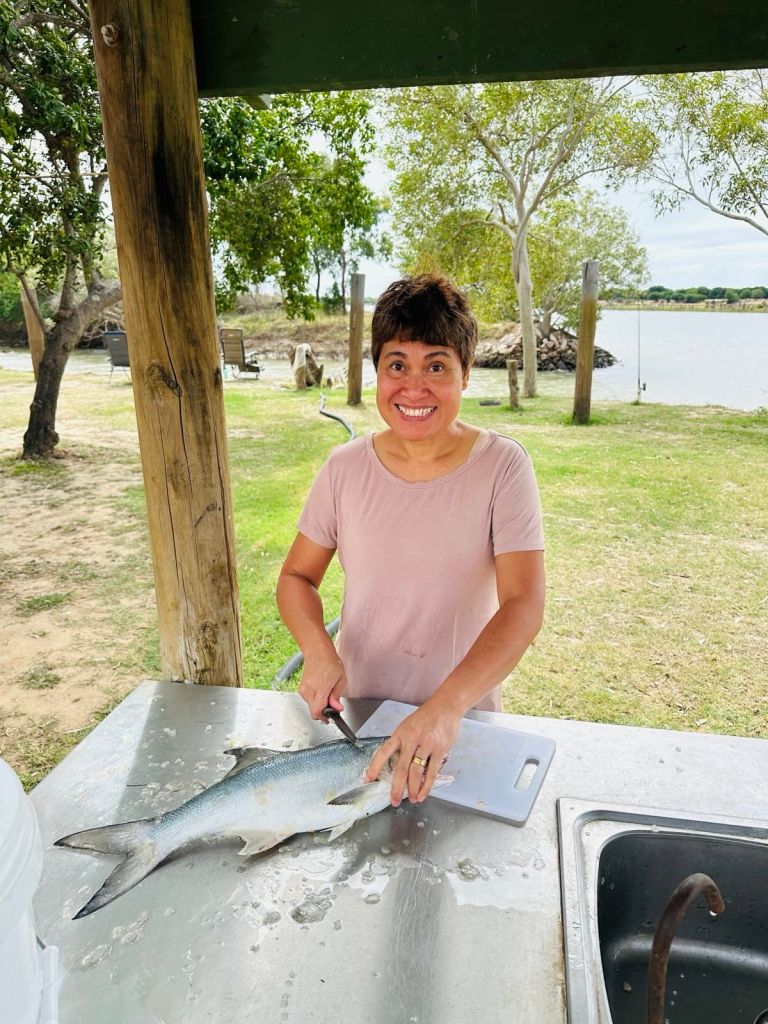 Mallie cleaning a blue salmon caught in Groper Creek behind.